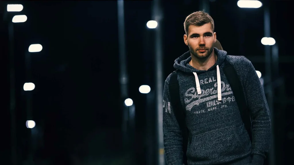 Musiker mit Gitarre auf dem Rücken an einem Bahnhof bei Nacht